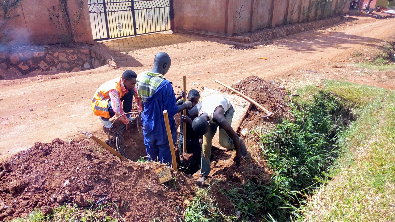 Fiber optic infrastructure workers servicing an underground access location in Uganda
