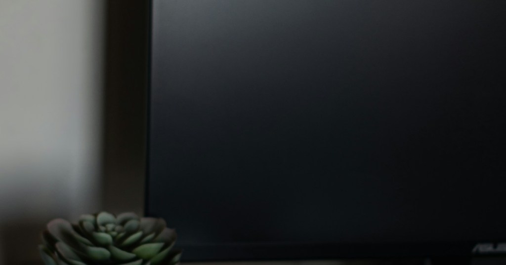Realistic editorial photograph of a gaming setup with a controller and monitor.