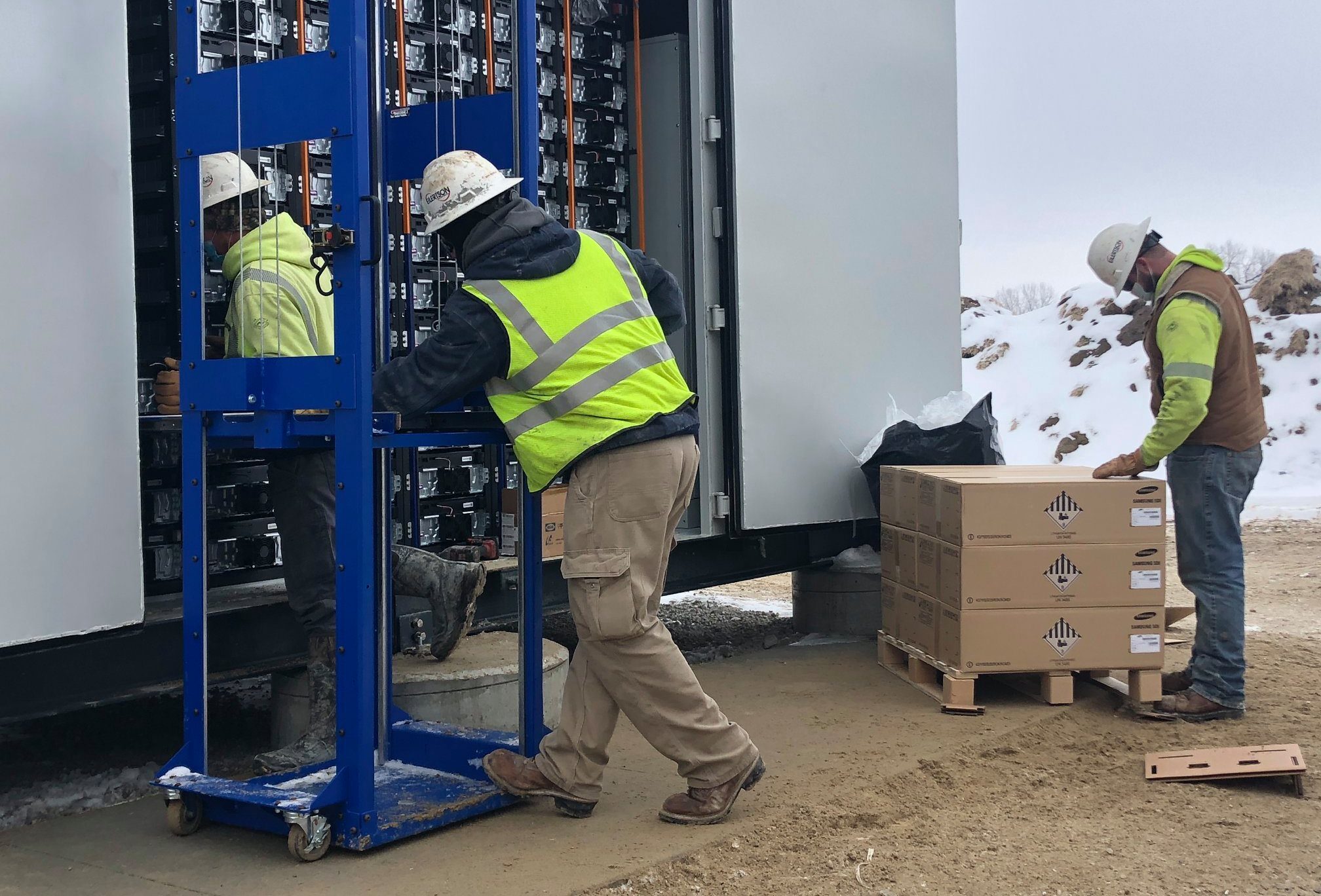 Technicians placing battery storage modules into an industrial energy storage enclosure