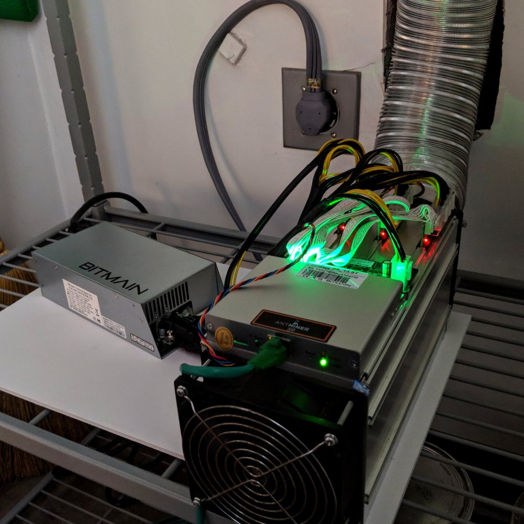 A Bitmain Antminer S9 Bitcoin ASIC miner with exposed hashboards and cooling fans.