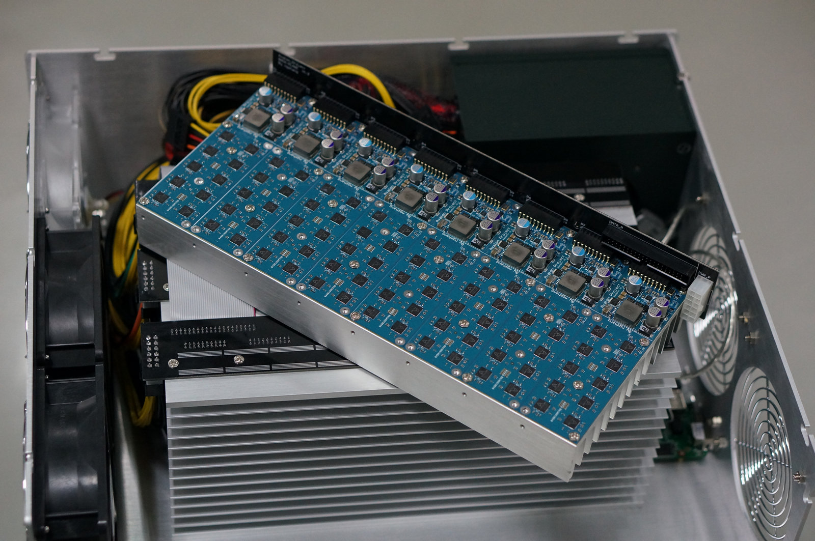 Historical 2013 Avalon Bitcoin mining ASIC board exposed inside the machine with blue PCB, components, heatsink, fans and cables