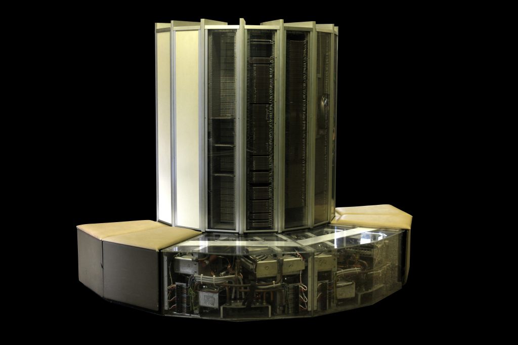 An original Cray-1 supercomputer with its distinctive C-shaped cabinet and padded bench surrounding the central processor cabinets.