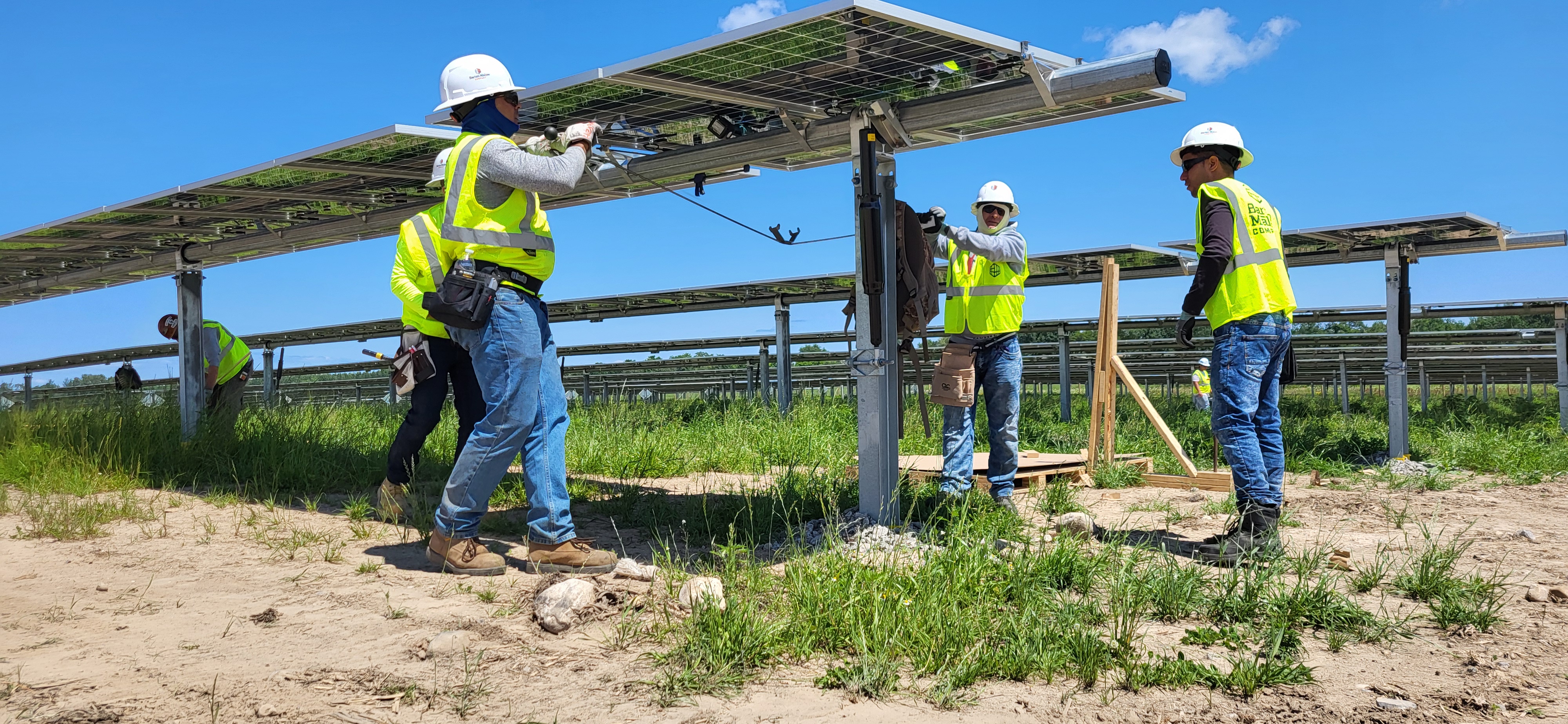 Two workers installing solar-panel mounting equipment at DTE's separate Little Trout Solar Park in Michigan
