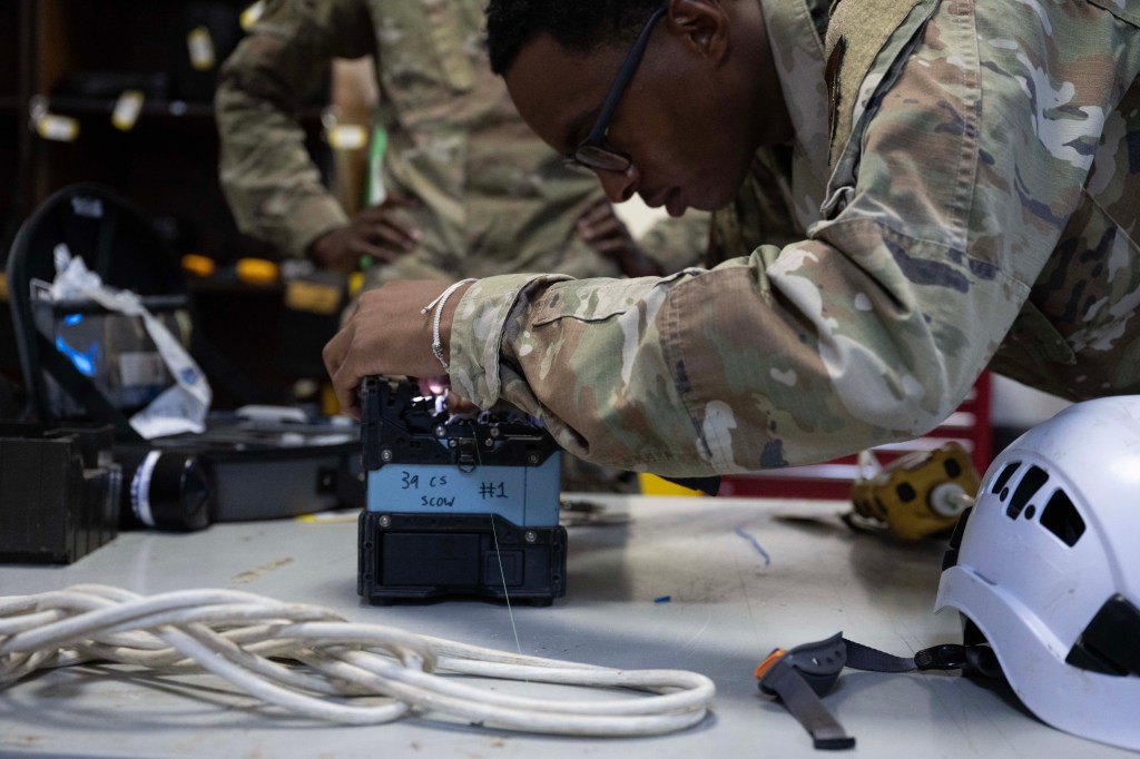 A communications technician operates a fiber-optic fusion splicer at Incirlik Air Base