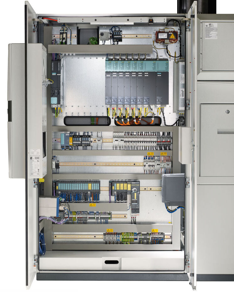 An industrial control cabinet containing Siemens PLC hardware, I/O modules, relays, circuit protection, terminal blocks, and Ethernet wiring.
