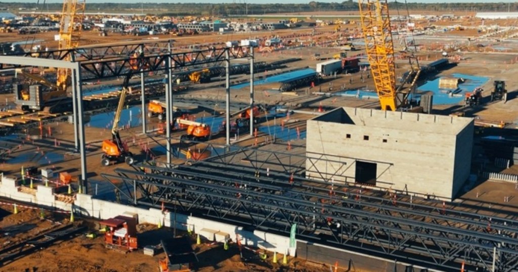 Detailed real construction scene at Meta Hyperion Richland Parish data center campus in Louisiana, showing cranes lifting steel frames and the expanding industrial building structure