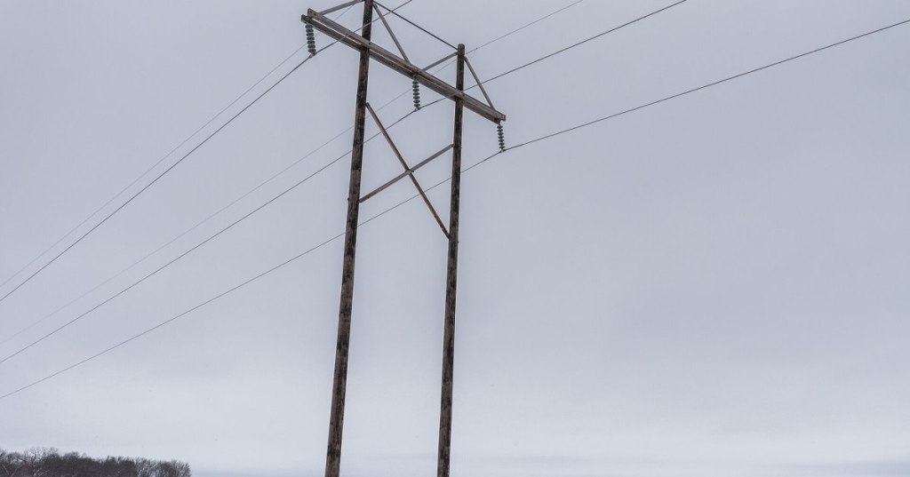 Documentary photograph of rural Minnesota electrical transmission lines over snowy farmland, representing grid infrastructure considered in data center power projects