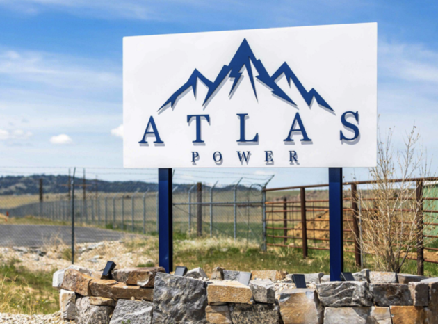 Photograph of the Atlas Power facility entrance sign, fenced property and rolling hills near Butte Montana