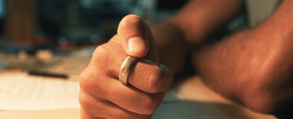 A person presses the button on Natura's Interface smart ring worn on the index finger.
