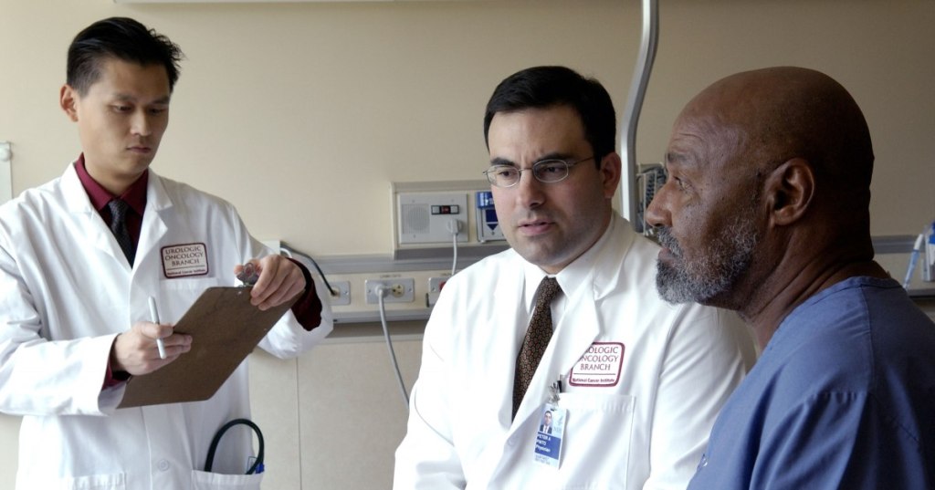 National Cancer Institute urologic oncology doctors consulting with a patient in a clinical setting.