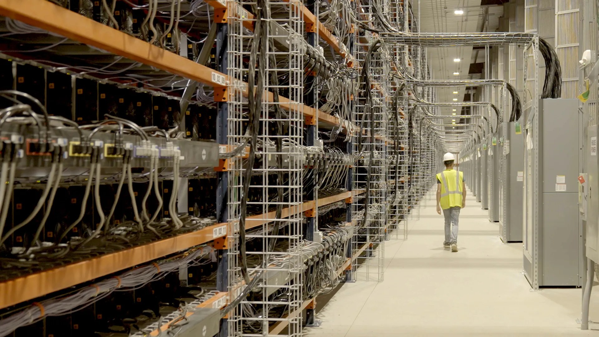MARA employee in a safety vest walking among electrical distribution cabinets inside a company computing facility