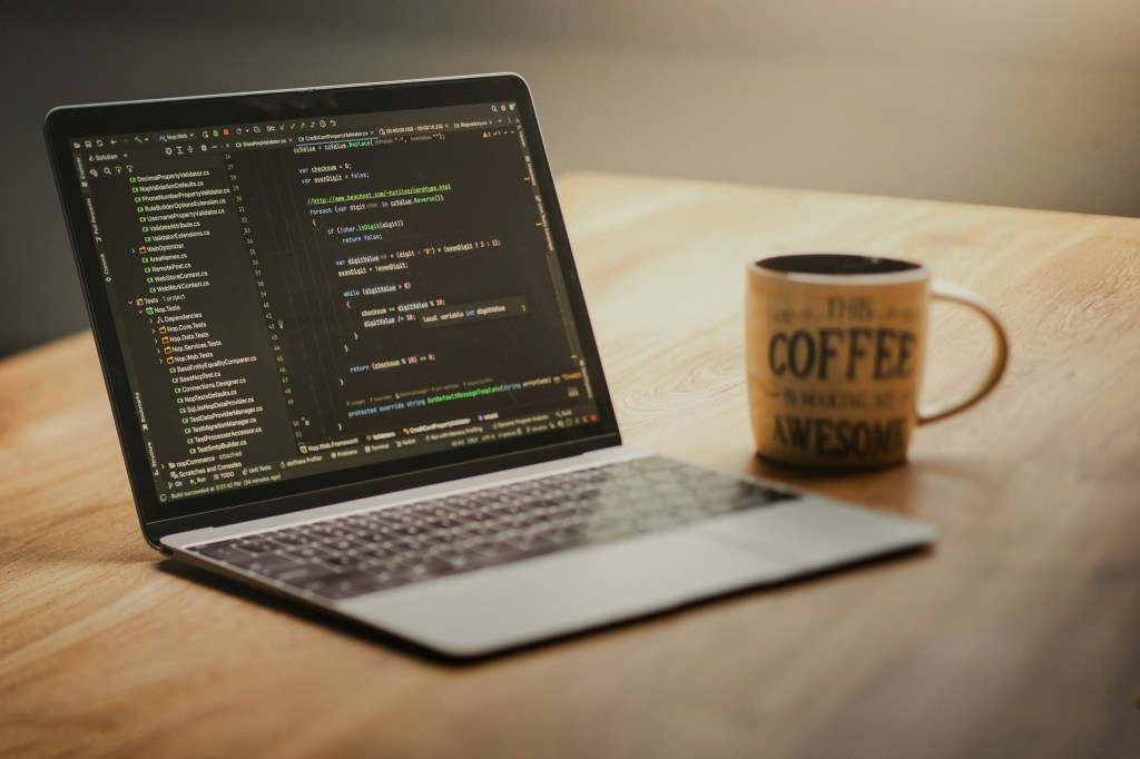 Laptop open with programming code and a coffee mug on a developer desk