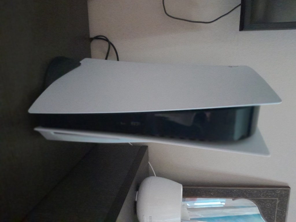 A Sony PlayStation 5 console photographed vertically, representing the hardware targeted by the open-source AnyPS5 compatibility project.
