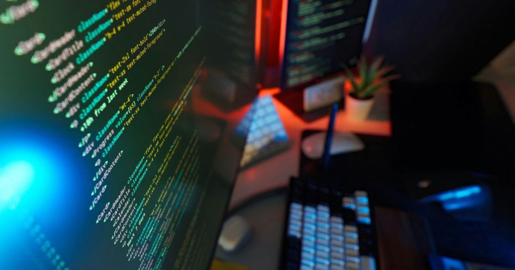 A dual-monitor software development workstation showing code in a dark studio