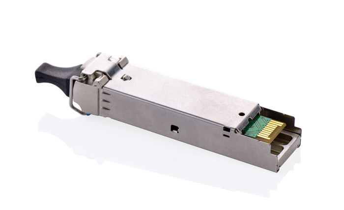 Close-up of a plug-in optical transceiver module with a metallic housing and gold connector