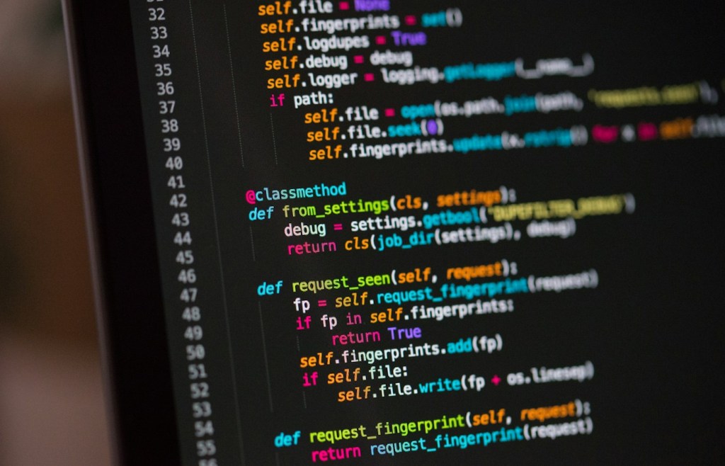 Laptop screen showing source code, representing applications making operating-system requests.