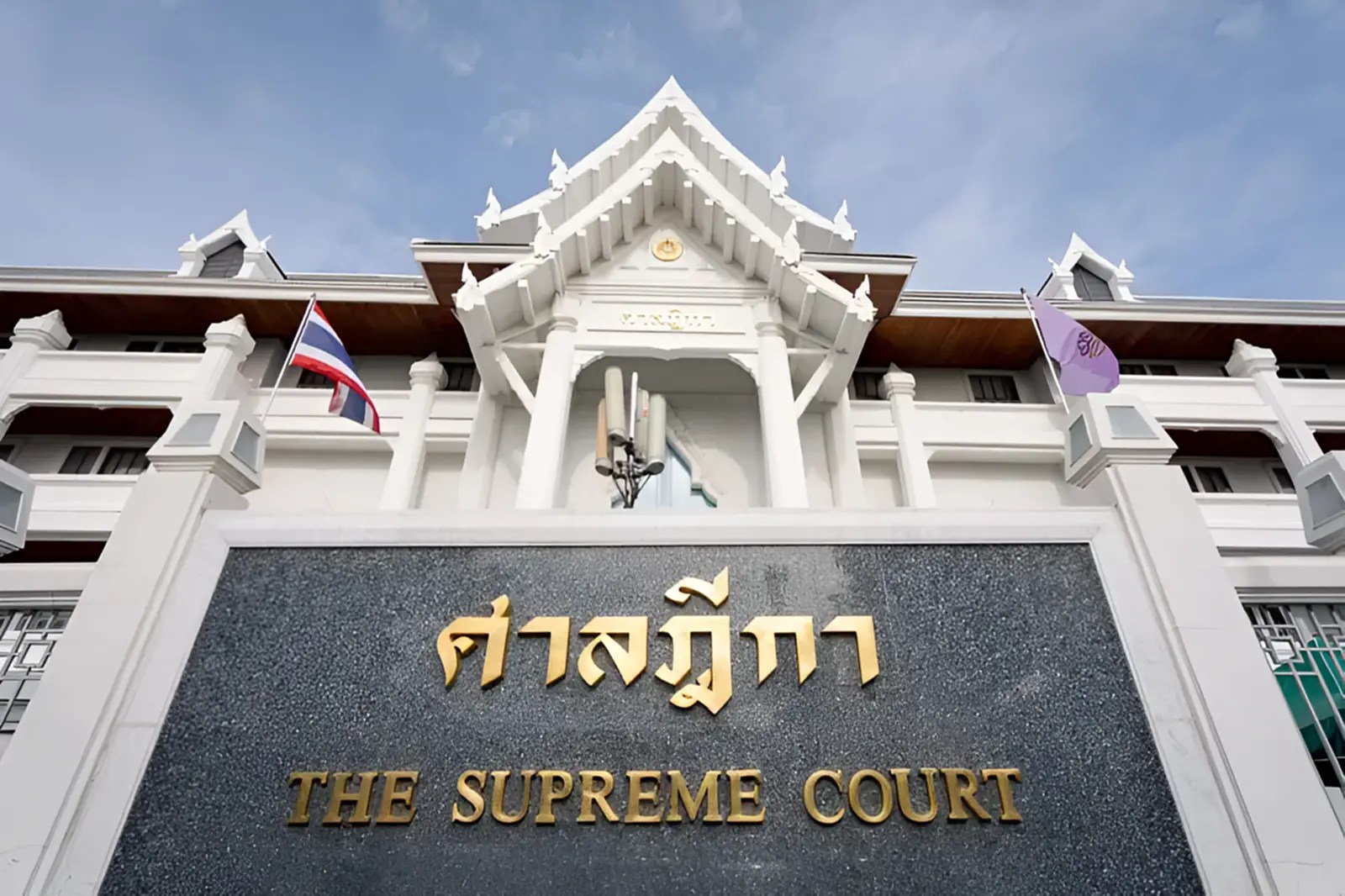 Exterior of Thailand's Supreme Court building with Thai national flag and court name in Thai and English