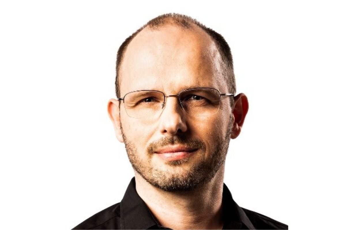 Portrait of Thomas Dohmke wearing glasses and a dark collared shirt