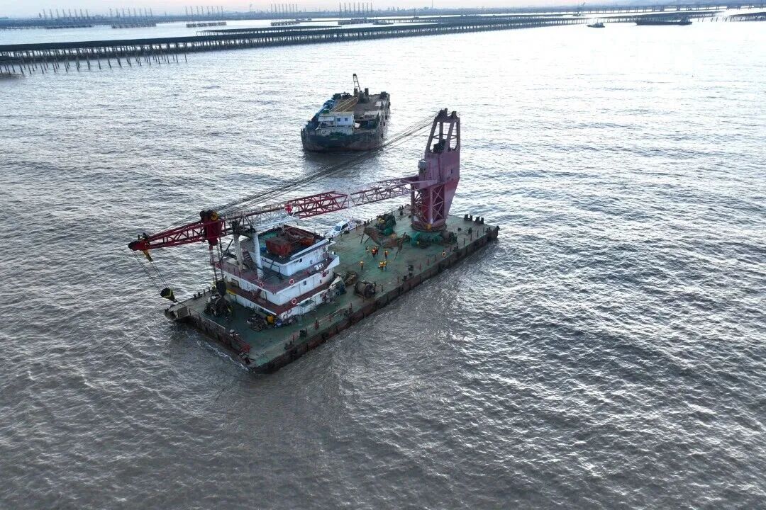 A marine construction crane barge working amid tidal-flat solar installation pilings in Jiangsu China