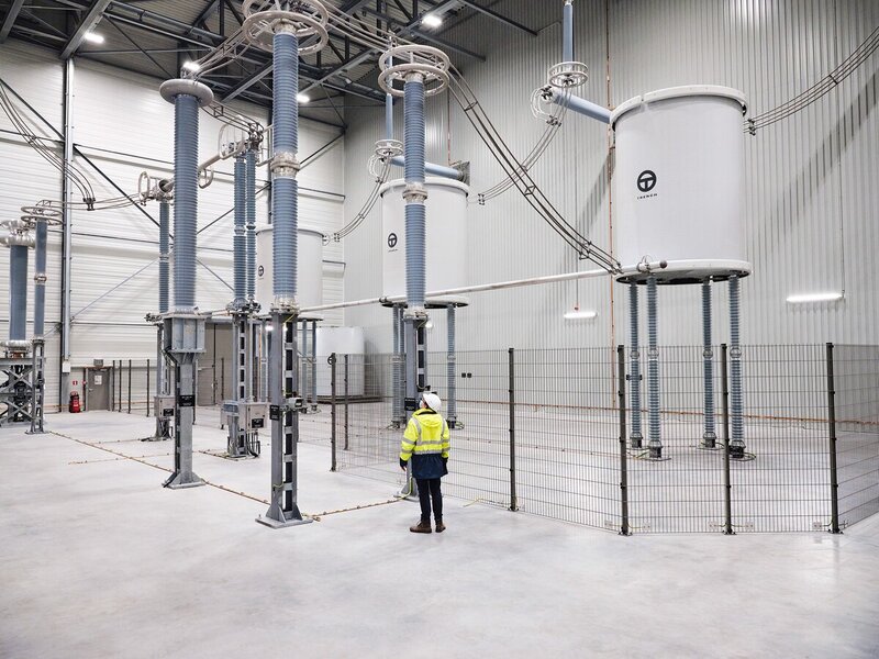 Technician inspecting large high-voltage coil and insulation equipment inside a Trench Austria facility