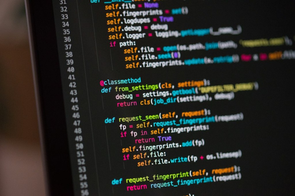 Computer screen and keyboard in a programming workspace.